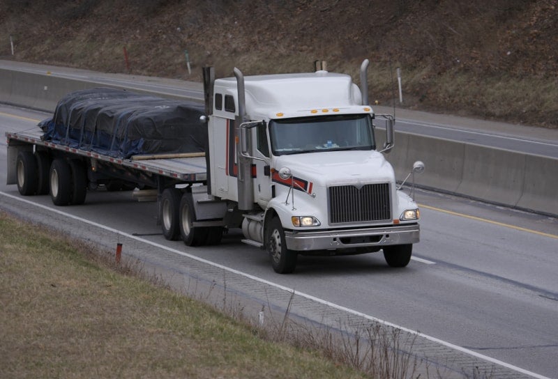 A tractor hauls a flatbed trailer and its load.