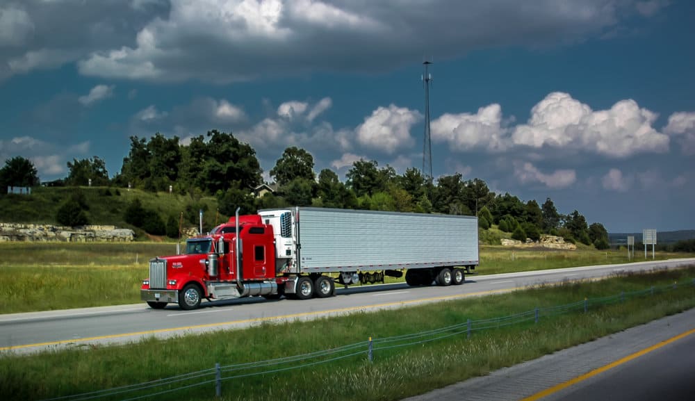 Red reefer truck on highway under blue sky