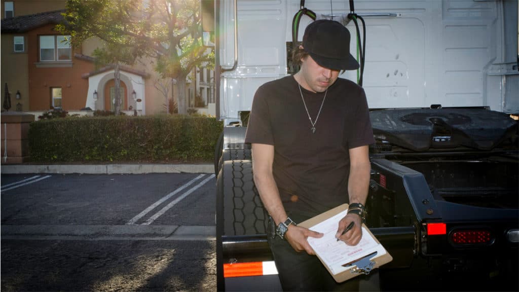 Truck driver filling out paperwork outside his rig. (Photo credit: Jim Allen/FreightWaves)