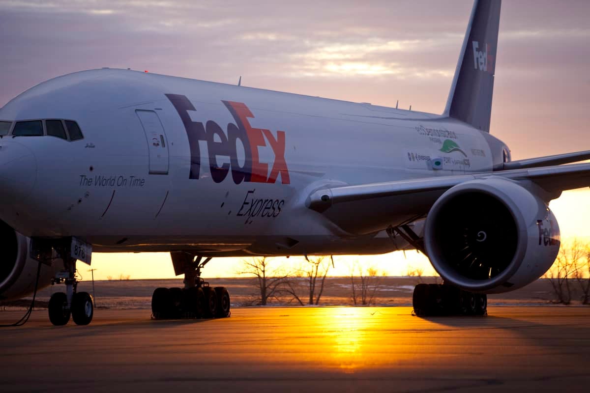 A FedEx airplane on a runway at sunset.