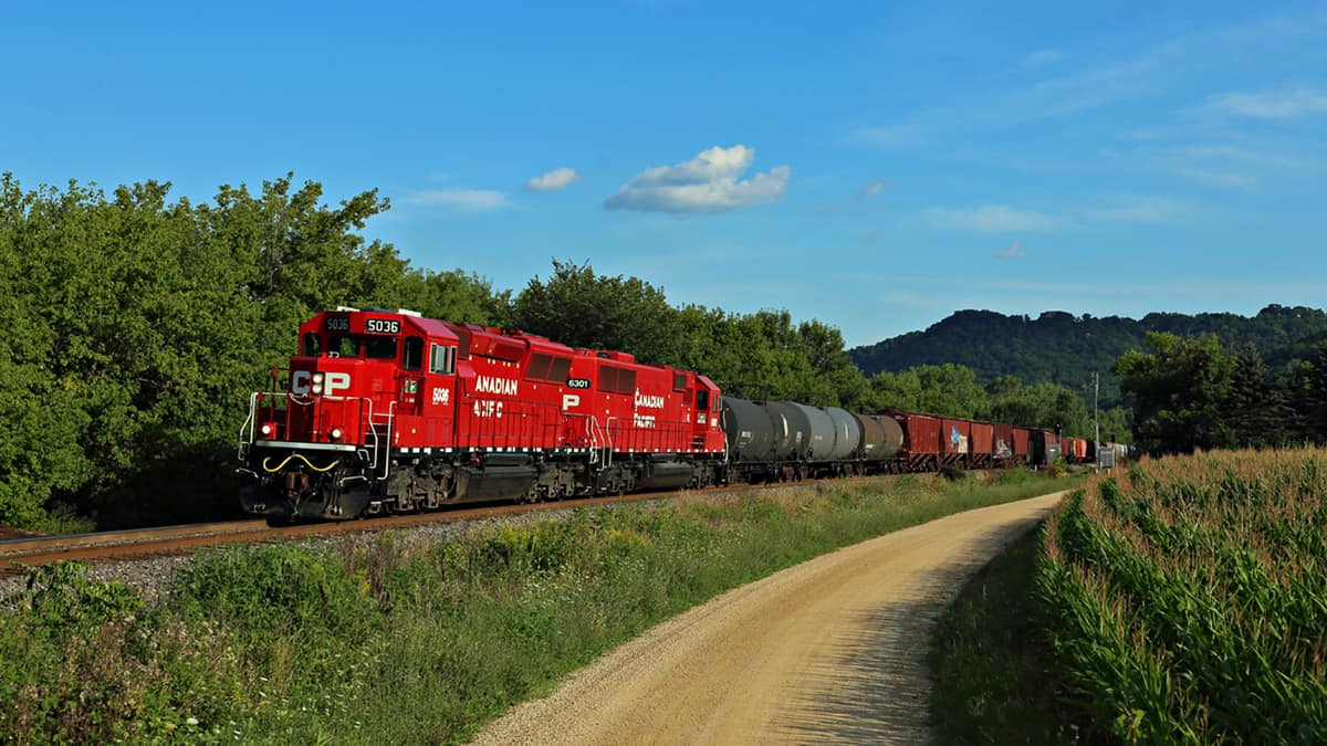 A photograph of a Canadian Pacific train crossing a grassy field.