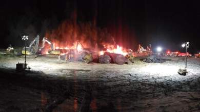 A photograph of fire burning next to some tank railcars. The photo was taken at night.
