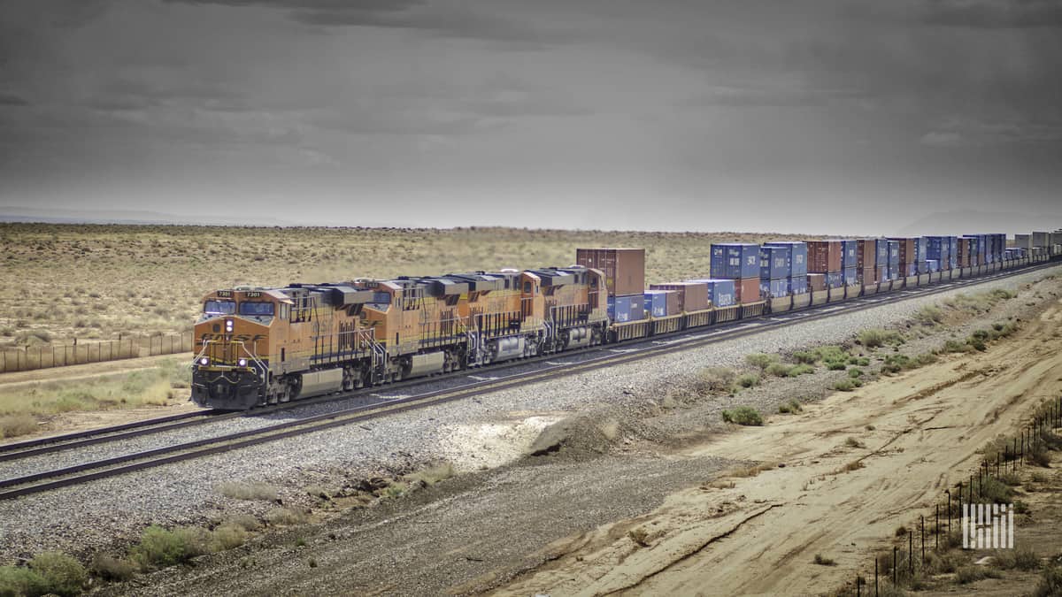 A locomotive is hauling container boxes through a field.