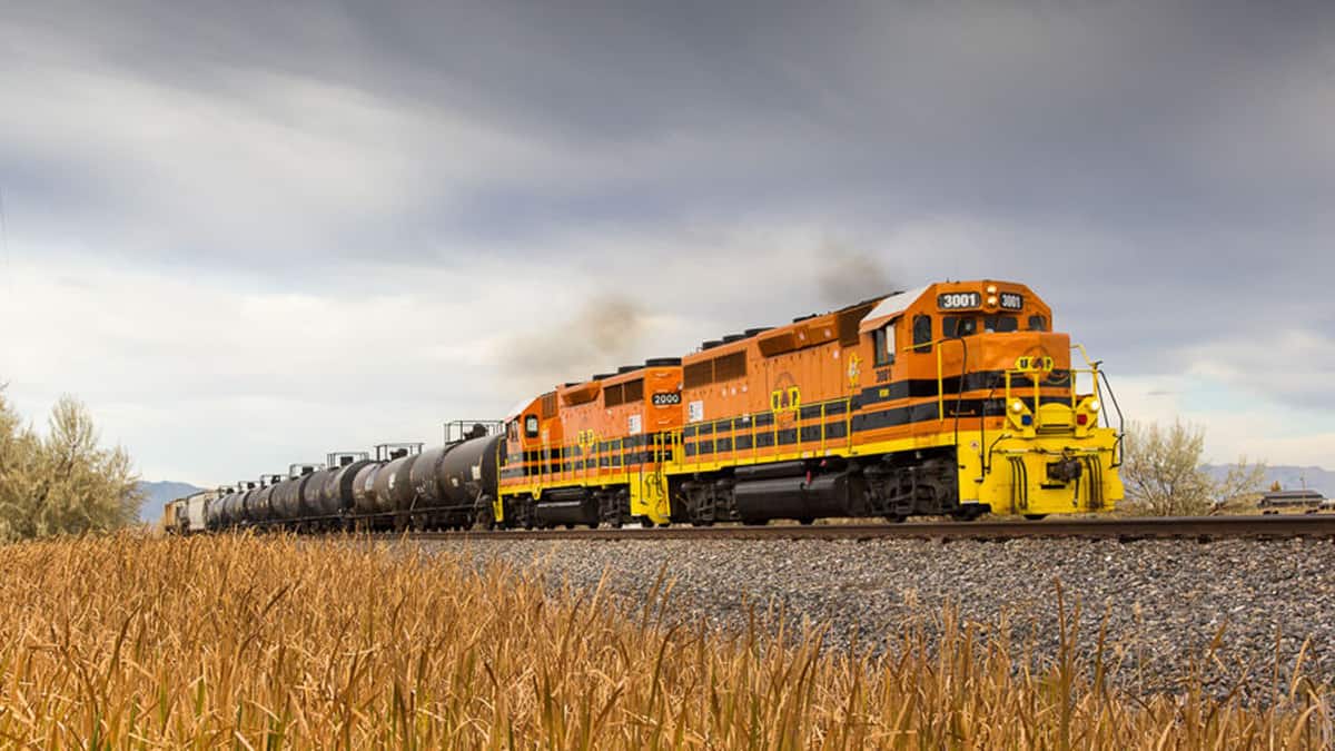 A photograph of a locomotive pulling tank cars across a field.