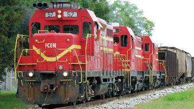 A photograph of a locomotive pulling two other locomotives and railcars,