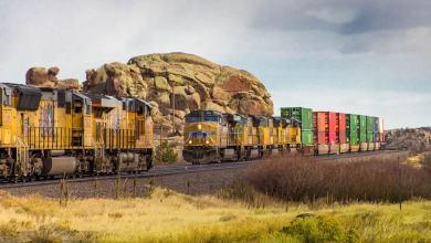 Two locomotives face each other on opposite tracks. One locomotive is hauling intermodal containers behind it.