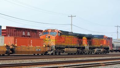 A photograph of a locomotive on a railway track. Intermodal containers are surrounding the locomotive.