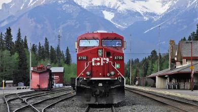 A photograph of a train with tall mountains in the background.