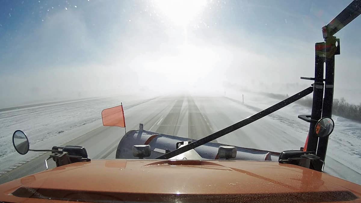 Plow truck going down snowy Iowa road.