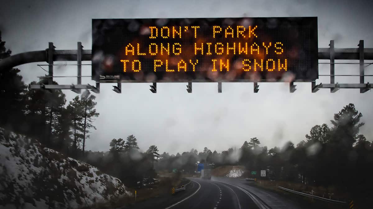 Digital highway sign warning of snowstorm.
