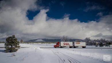 Tractor-trailer moving through snowy area.