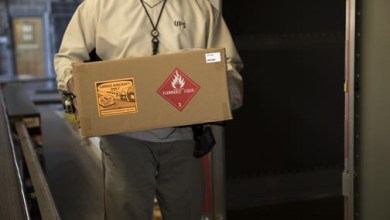 Warehouse worker holding box with a hazmat label on it