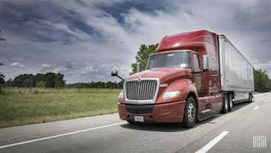 Red truck driving on highway in rural area