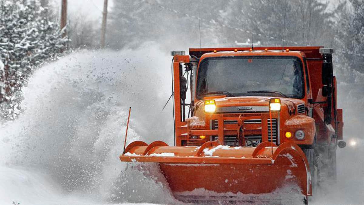 Plow clearing very snowy road in New Hampshire.