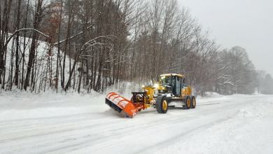 Plow clearing snowy New Hampshire road.