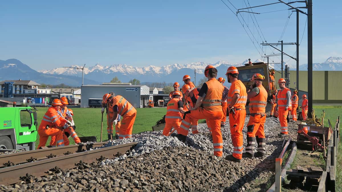 A photograph of a group of uniformed people standing next to a railroad track.