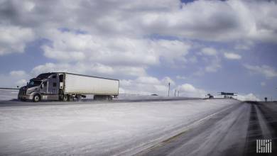 Tractor-trailer heading down snow-covered highway.