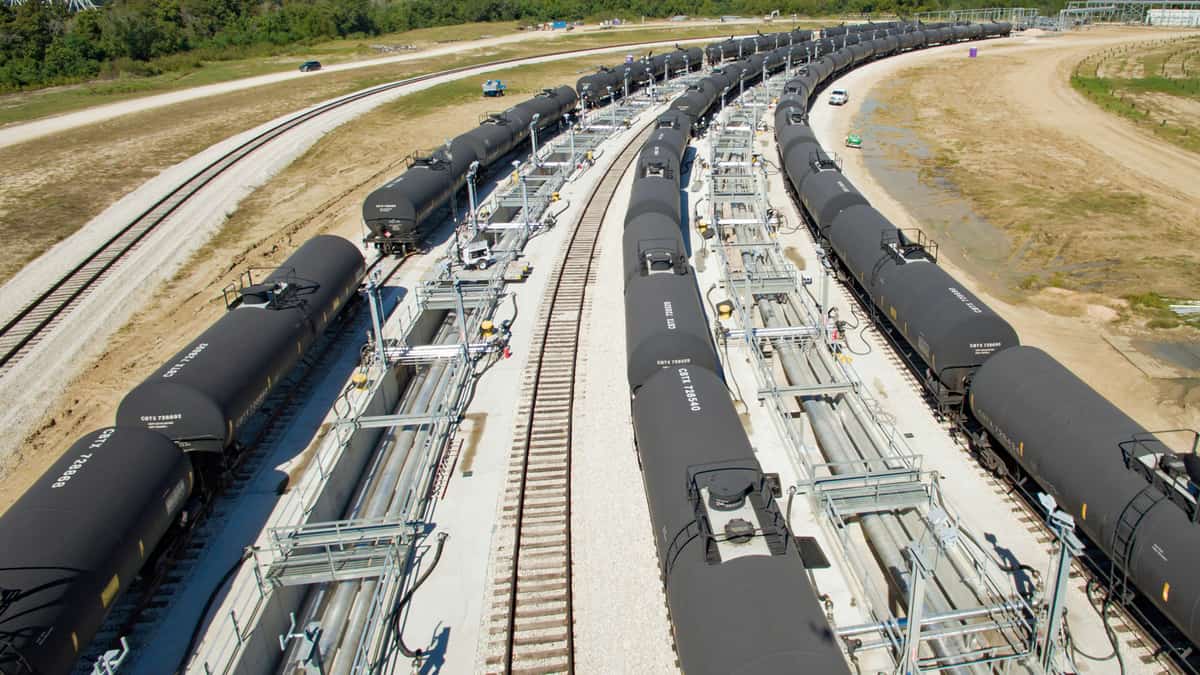 A photograph of three long lines of tank cars sitting at a rail yard.