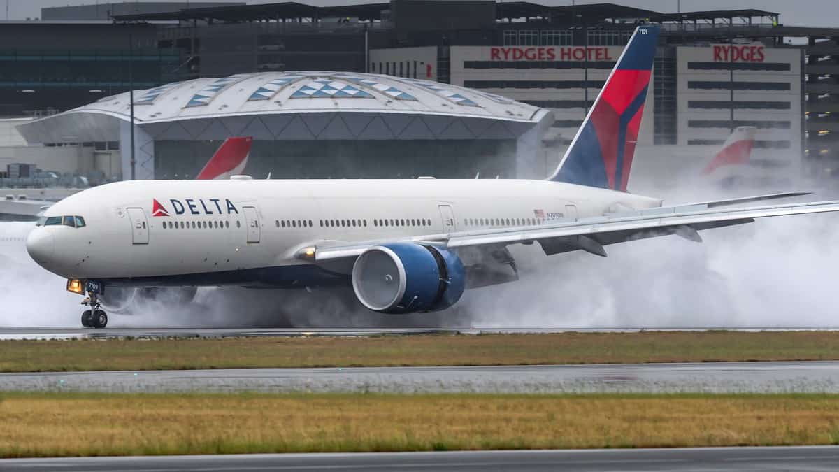 Smoke comes from wheels as big jet touches down on runway.