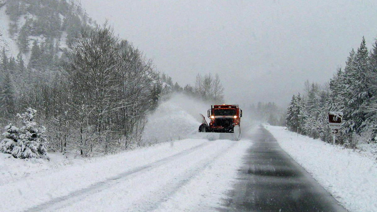 Plow clearing snowy highway in Montana.