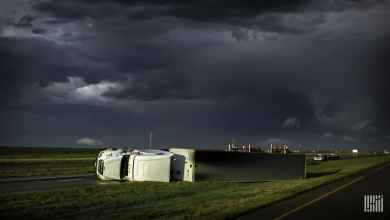 Tractor-trailer flipped over on side of highway.