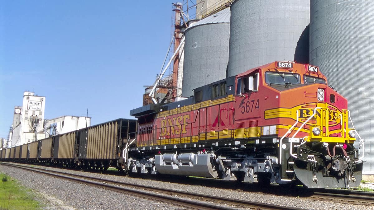 A photograph of a train in front of silos.