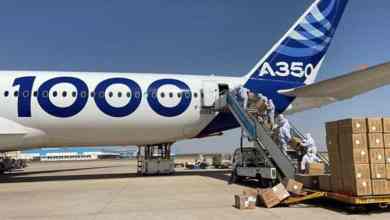 A large white plane gets loaded with boxes of face masks.