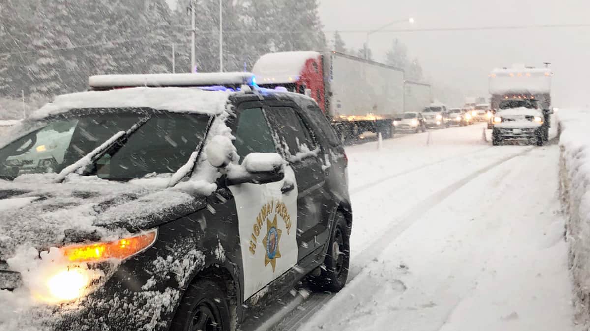 Tractor-trailers and cars stuck on snowy California highway.