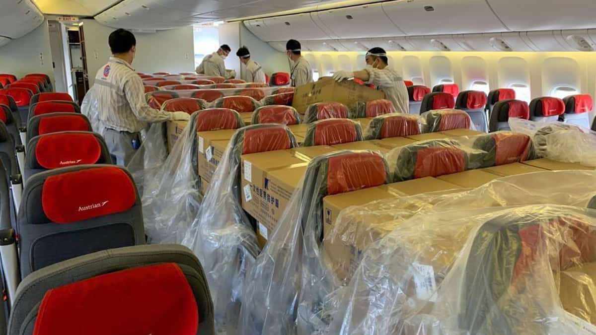 Austrian Airlines cargo handlers loading freight in the seats of a passenger airplane.