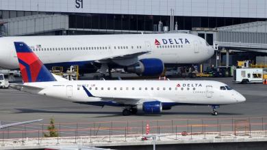 A big white Delta jet next to a smaller one at airport.