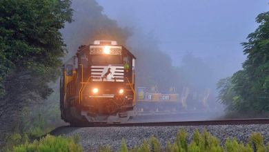 A photograph of a locomotive engine hauling railcars through the fog.