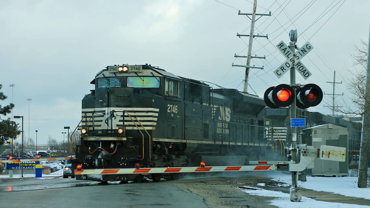 A photograph of a train at a railroad crossing.