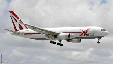 Big white jet with wheels down for landing.