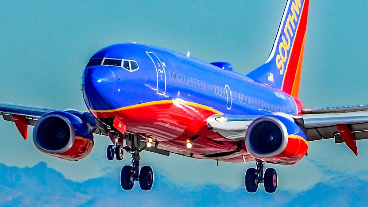 Bright blue and orange Southwest jet comes in for landing wheels down.