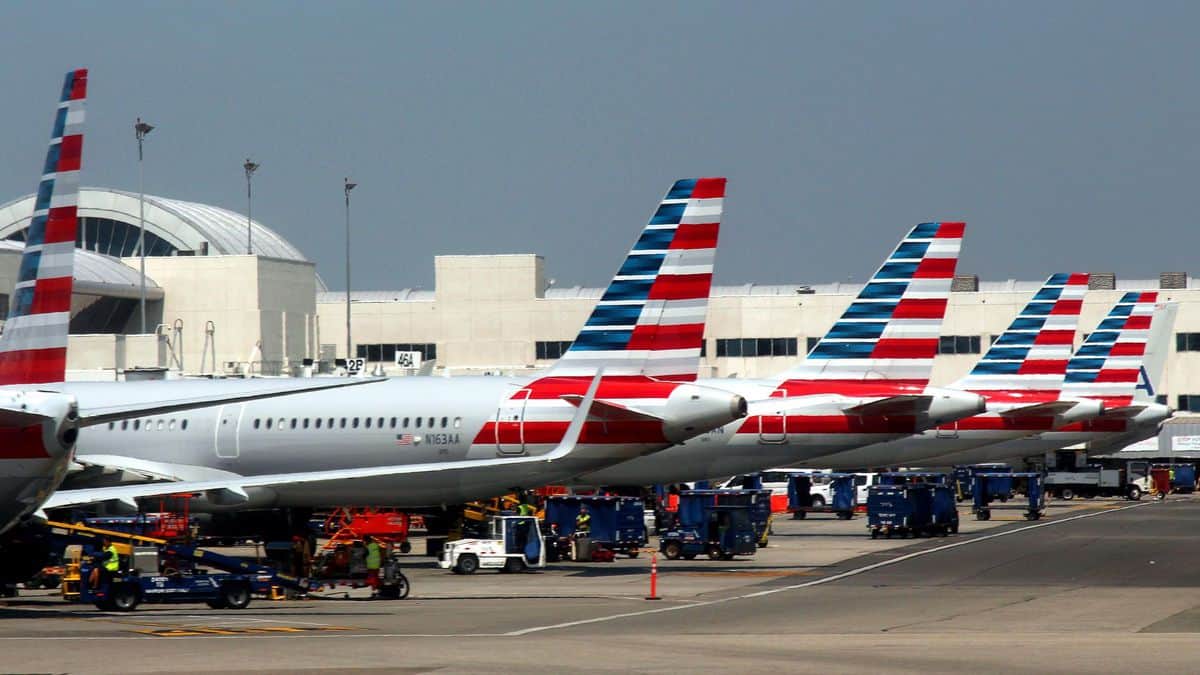 Red, white and blue tails of American Airlines planes at terminal gates.