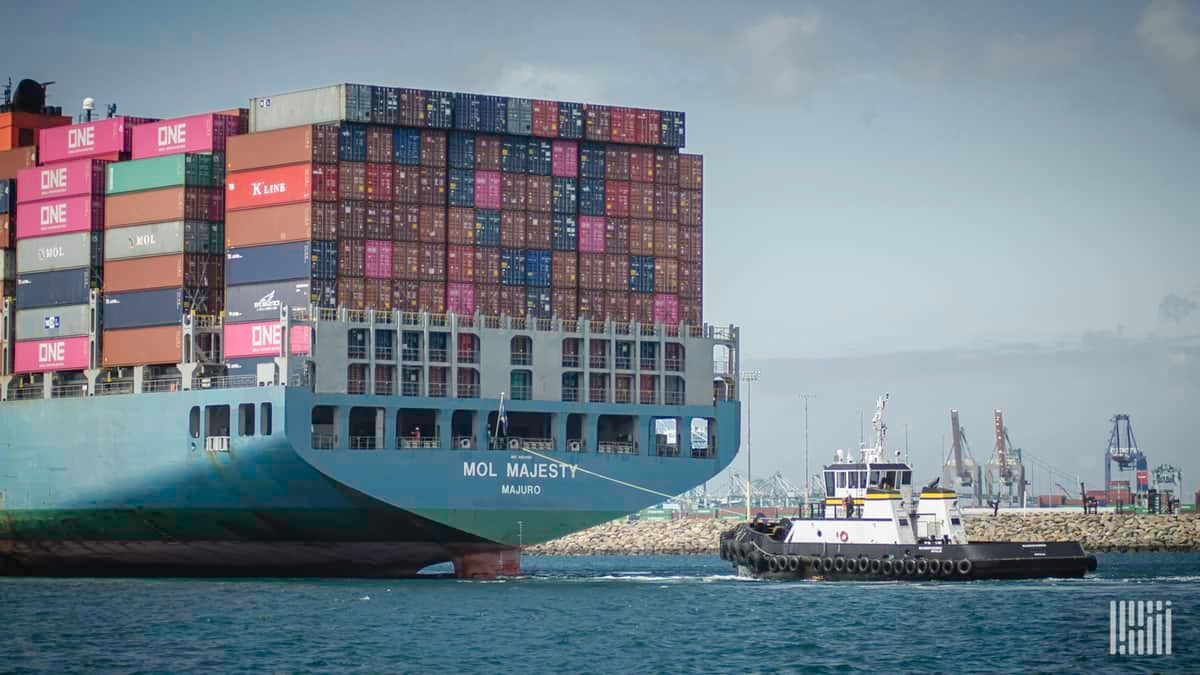 Cargo ship and tugboat in a harbor.