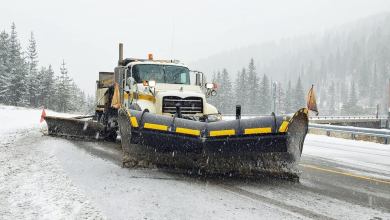 Plow clearing snowing Idaho highway.