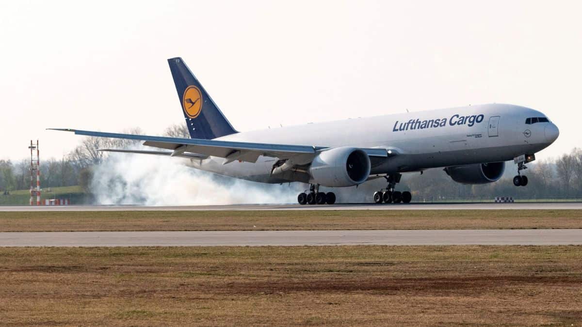 A white Lufthansa plane touches down on runway.