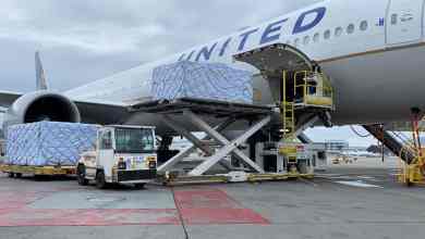 A big white jet gets loaded with pallets of cargo.