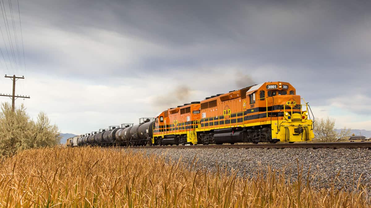 A photograph of a train hauling tank cars across a field.