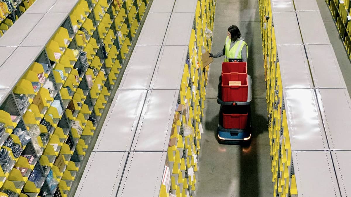 A warehouse worker with a robot at a Shopify fulfillment facility.