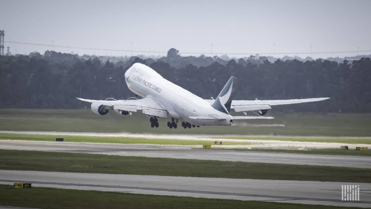 A big white jet heading away lifts nose off runway