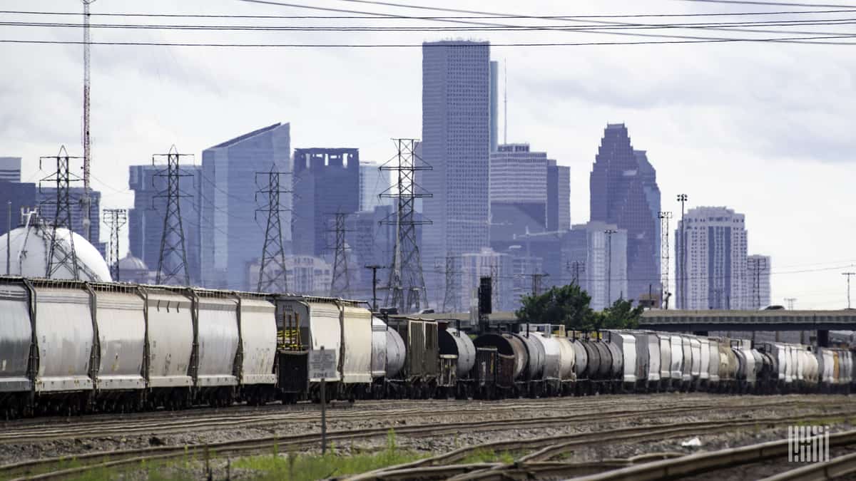 A freight train sits in a marshalling yard near a major city.