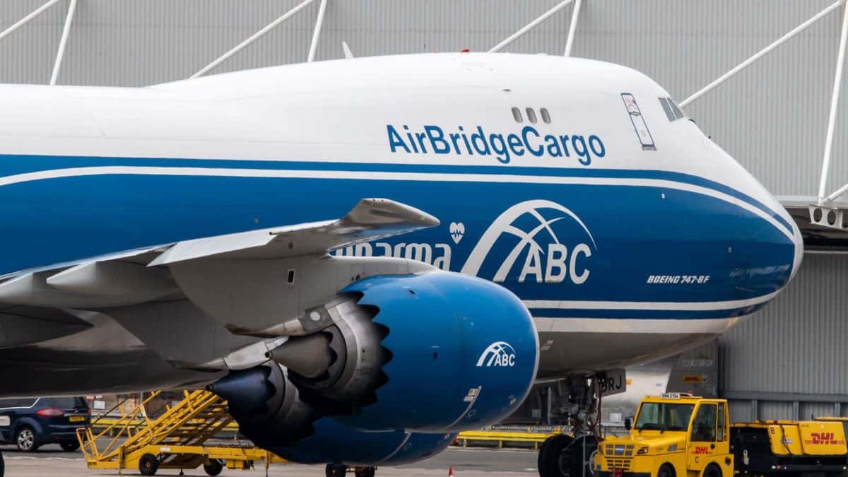 A blue-and-white 747 jumbo cargo jet parked at airport.