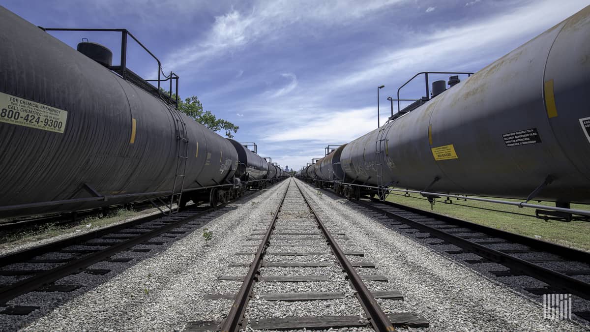 A photograph of tank cars in a rail yard. The tank cars are in lined up left and right.