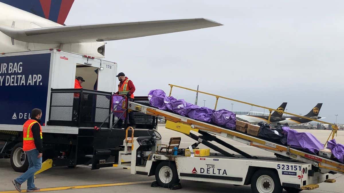 Mail bags being loaded with a conveyor onto a passenger airplane.