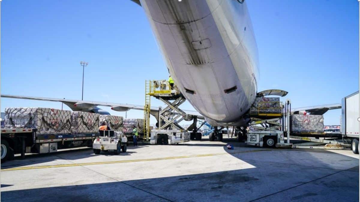 Large cargo plane being loaded, view from underbelly at tail end.