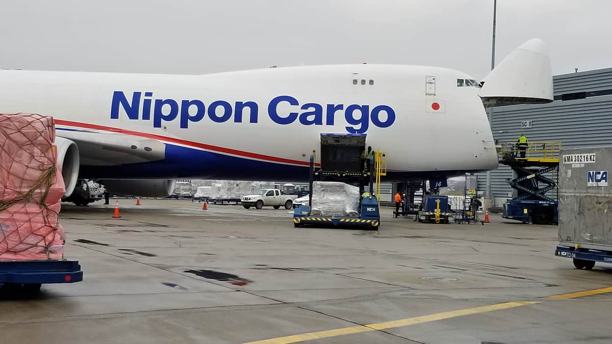 Big white 747 freigher with nose cone up to load cargo.