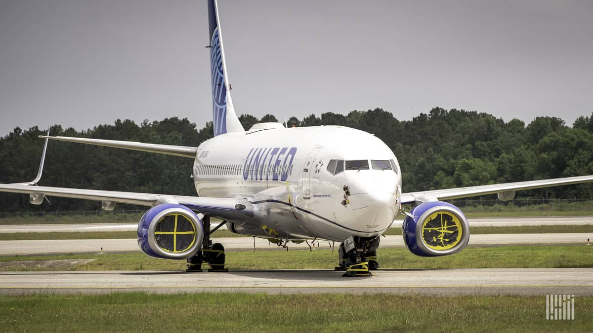 A white United Airlines plane in storage on tarmac.