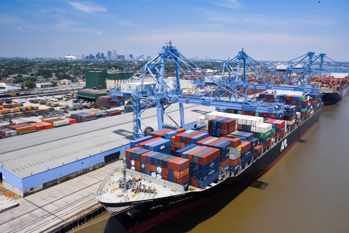 A photograph of a cranes unloading containers from an ocean vessel.